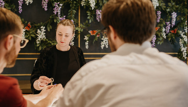 A sales assistant is showing engagement rings to a gay couple.